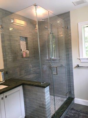 Frameless shower mounted to glass tile with knee wall