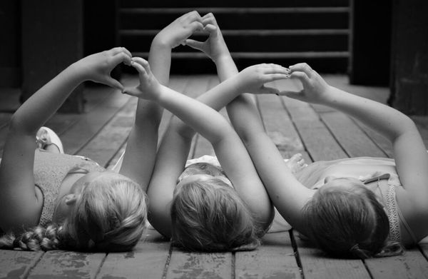 Three best friends, intertwining arms to use each others hands to form three hearts.