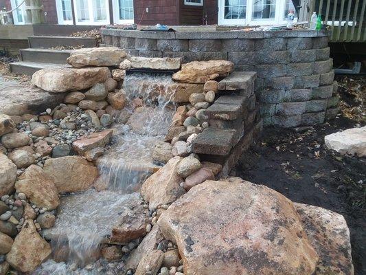 Water fall built in front of a retaining wall.