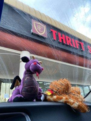 Stuffed animals in front of thrift store sign.