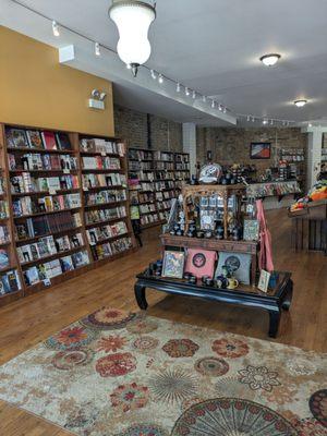 A store glimpse. Left, manga. The table displays merch, even candles! In the back, there are American and children's sections.