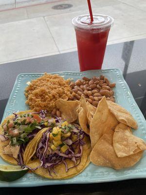 Combo plate with a shrimp taco, a mahi taco, chips, beans, rice, and watermelon agua fresca