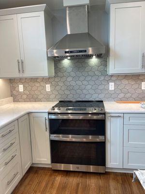 Kitchen remodeling project with new painted perimeter cabinets with a stained maple island, new quartz countertops, and a new backsplash.