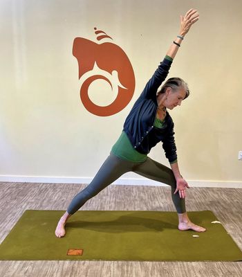 Sally in Warrior pose in front of our beautiful Ganesh symbol~ check out our full schedule of classes!