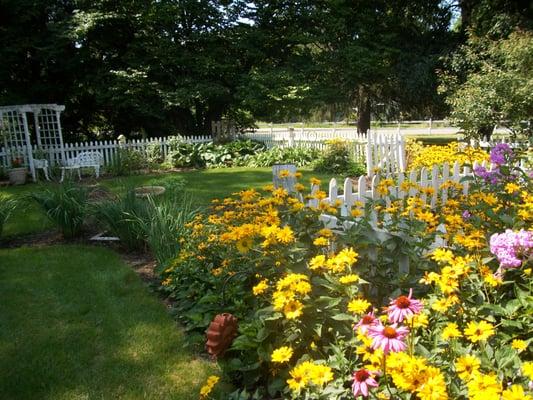 Quaint white picket fenced gardens to enjoy located right off the covered porch.