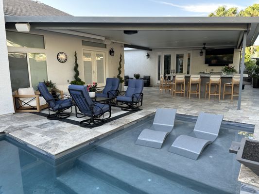 Covered outdoor kitchen with movie screen, bar tv, smoker and pool sun deck.