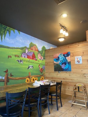 Mural with seating area and cow painting.