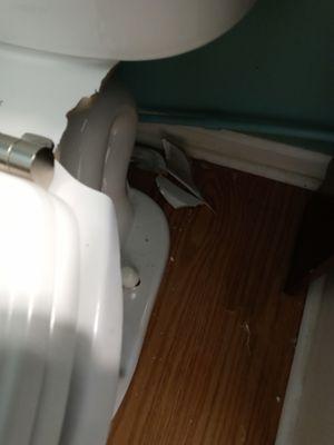 Broken toilet; pieces on floor.