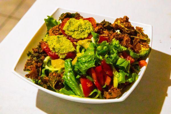 Salad with raw vegan burgers and heated tomatoes with green sauce