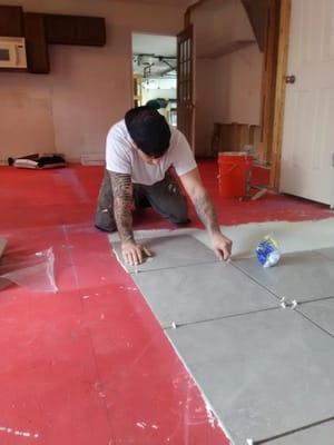 Laying down mortar and tile over concrete kitchen floor.