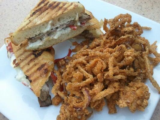 Yummmmm... tendorloin panini with carmelized onions, red peppers and blue cheese aioli with fried onion strings.