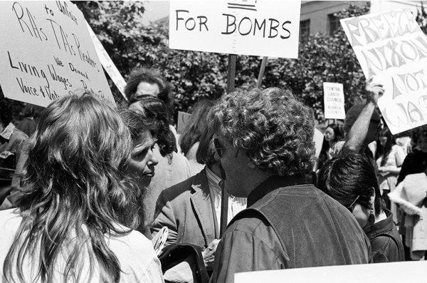 Protesters at entrance of U.C. Berkeley campus with signs that protest Nixon and bombs. - - -Tom Brody