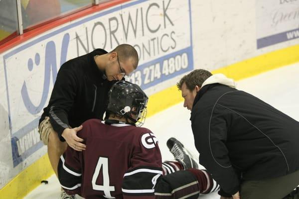 Garrett assessing a hockey player who was injured during a high school game.