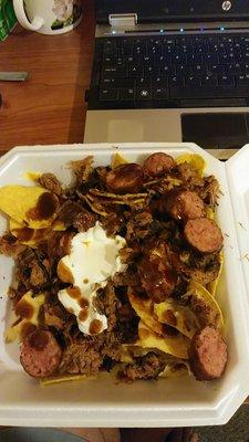 HUGE brisket nachos. Added some sour cream and smoked sausage.Taste heaven. Get a side of bbq sauce to drizzle on them.  Finished half of it