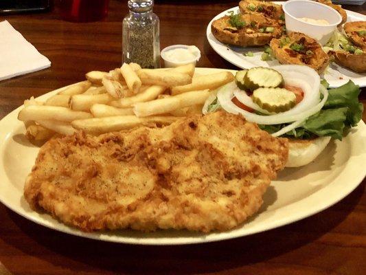 Pork tenderloin with french fries, potato skins appetizer in background