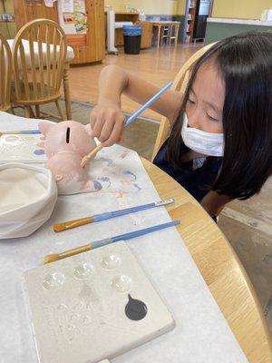 My daughter painting her piggy bank