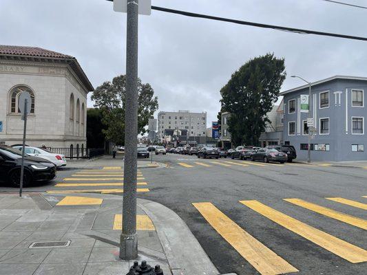 Line of traffic taking up the whole block next to the library--two lanes, the empty lane goes straight ahead, the full lane is a turn lane