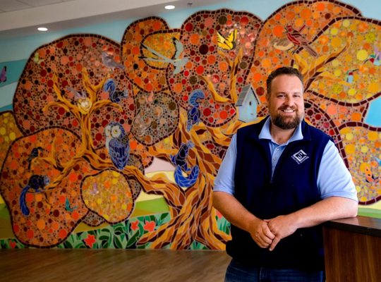 Artist Nick Bayer standing with his art installation Family Ties.