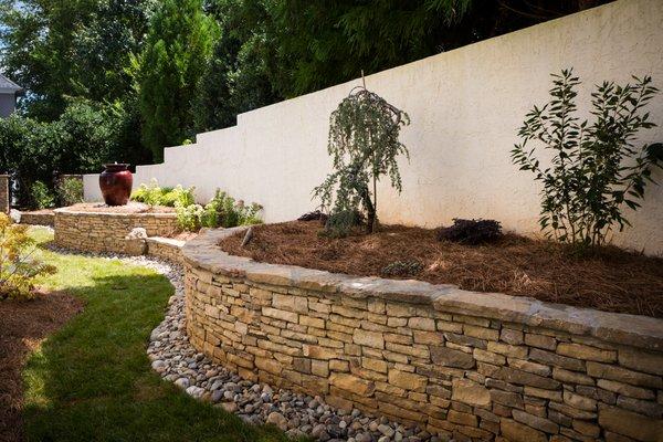 New Smoky Mountain veneer stone walls with new plantings and a water feature.