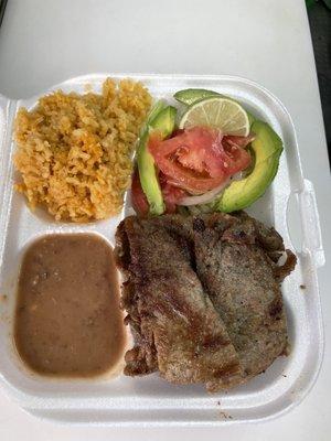 Carne asada platillo (food plate) with rice and beans, and tortillas on the side.