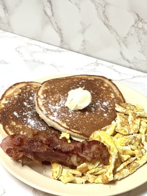 Pancake plate, 2 pancakes, 2 scramble eggs or over easy and 2 strips of bacon .