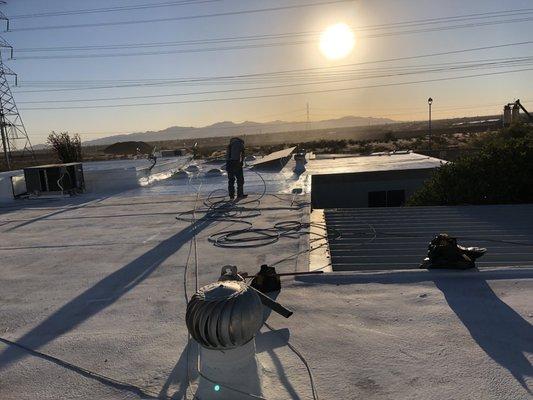 Applying heavy coat of Elastomeric Roof coating to  surface of flat roofs