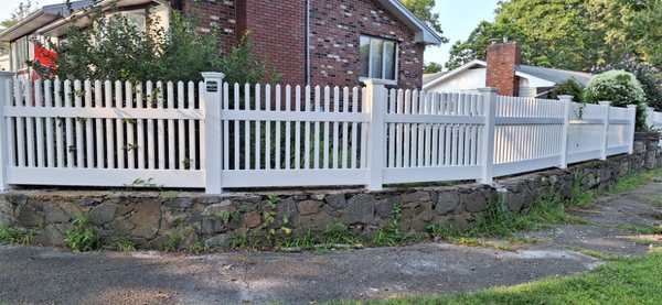 White vinyl classic pickets on the rock wall