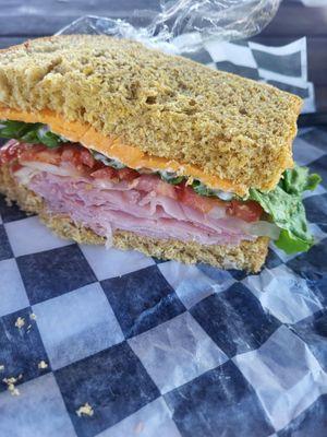 Honey ham and Cheddar cheese sandwich on homemade whole wheat bread with mayo, lettuce,  tomato and onion.