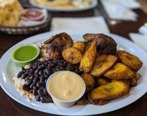 Half chicken hidden by plantains and black beans and rice