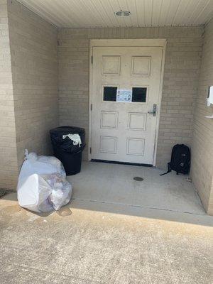 Entrance to drop off and pick up patients lined off with trash and a filthy door.