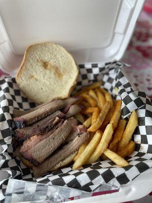 Sliced brisket sandwich with seasoned fries .