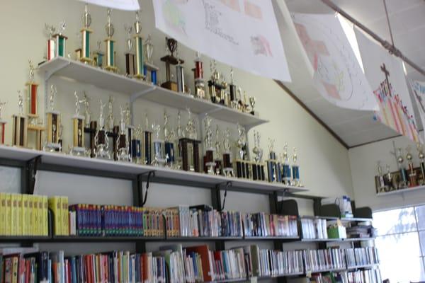 Some of the trophies our students have won and a portion of the library books.