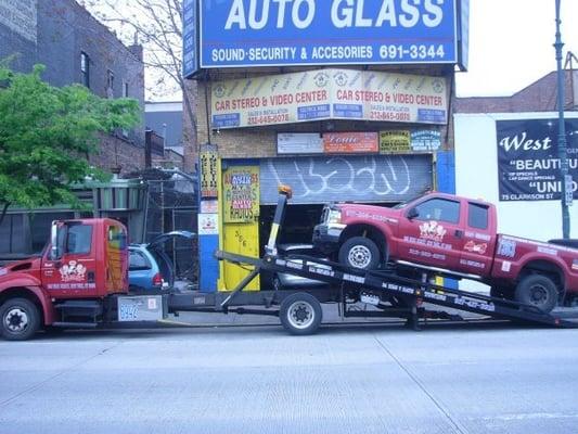 A flatbed truck towing a tow truck