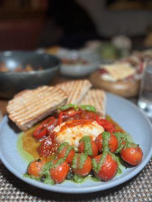 Buratta with a spiced tomato jam, roasted on-the-vine cherry tomatoes, garlic sourdough, and basil.