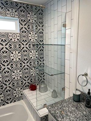 Frameless shelves connected to a frameless shower panel with a curtain rod above