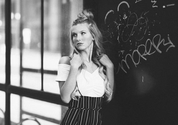 Black and white image of an attractive woman with blond hair posing for her senior portrait session