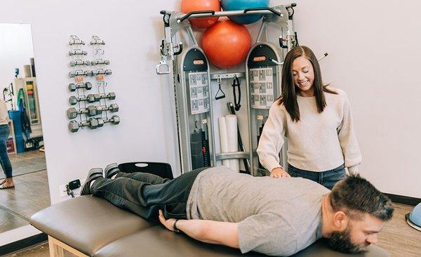 Occupational therapist ensuring patient performs exercise correctly in St. Paul rehabilitation gym.