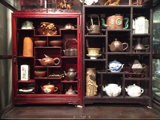 Rosewood curio cabinets with various pottery teapots and accessories.