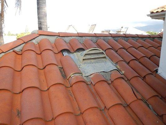 Improperly pitched dormer roof vent, louvers lean back and are susceptible to wind driven rain into attic. Broken & slipped roof tiles.