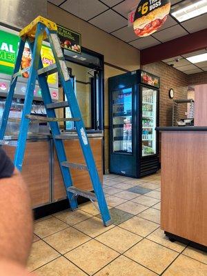 Broken drink machine with a ladder blocking the walk path......serious trip hazard