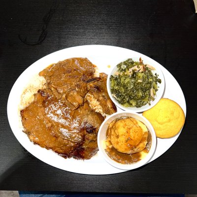 Smother pork chops on a bed of white rice with a side of mustard greens mashed potatoes and cornbread