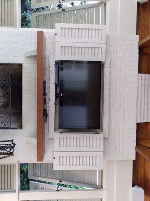 Full motion wall mounted TV above a fireplace outside by the pool.