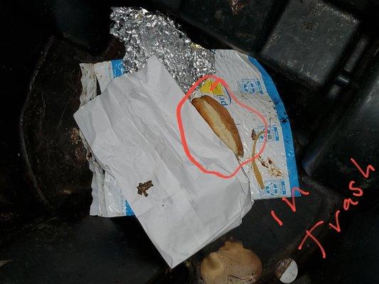 The not really strong style hot dog lying at the bottom of the trash can