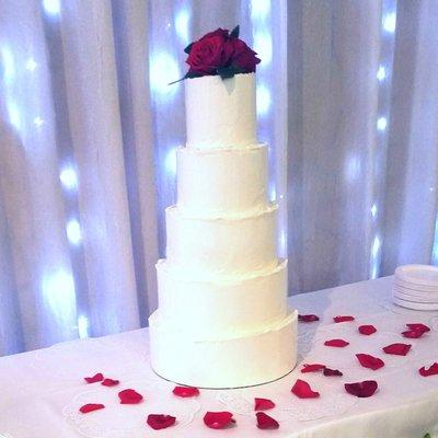 Simple and elegant 5 tier wedding cake with red roses and the royal rough iced edges.