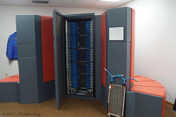 Cray Y-MP. The cabinet is open to show you the rack that held multi-layered circuit boards, an example shown on the floor.