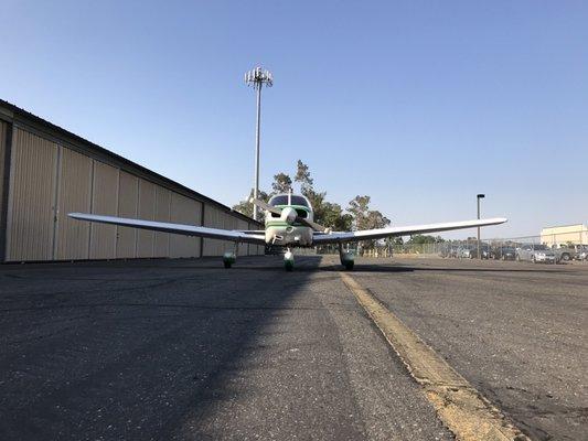 Piper Warrior in front of hangars