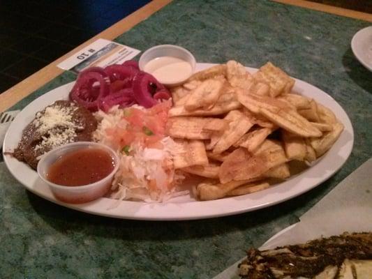 Side dishes for Honduran fish platter: (clockwise from left) bean puree, pickled onions, sauce 1, fried bananas, coleslaw, sauce 2