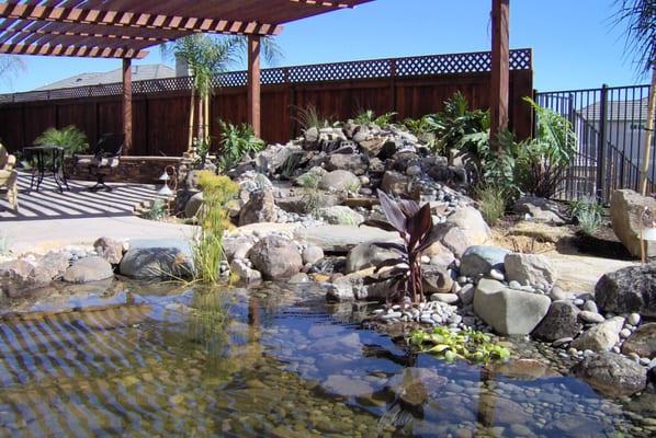 Custom waterfall, bridge and pond. Custom seatwall, concrete and flagstoe. Beautiful redwood shade structure