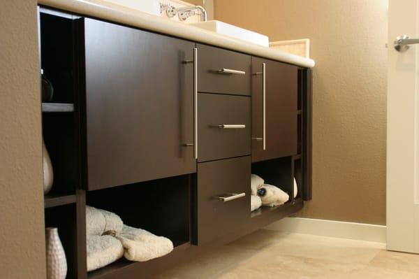 Floating bathroom cabinets with contemporary stainless handles and a flat door.