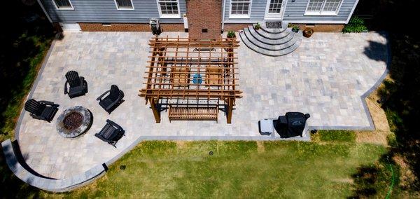 The backyard oasis project includes the paver patio, half moon stairs, fireplace, pergola, and a has fire pit.